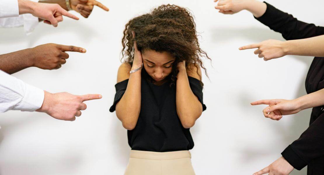 Woman covering her ears and being pointed at by different people
