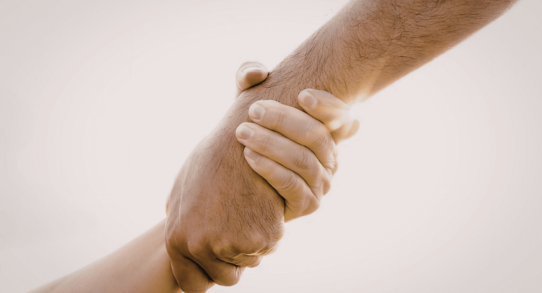 Hand reaching out to another who holds it firmly