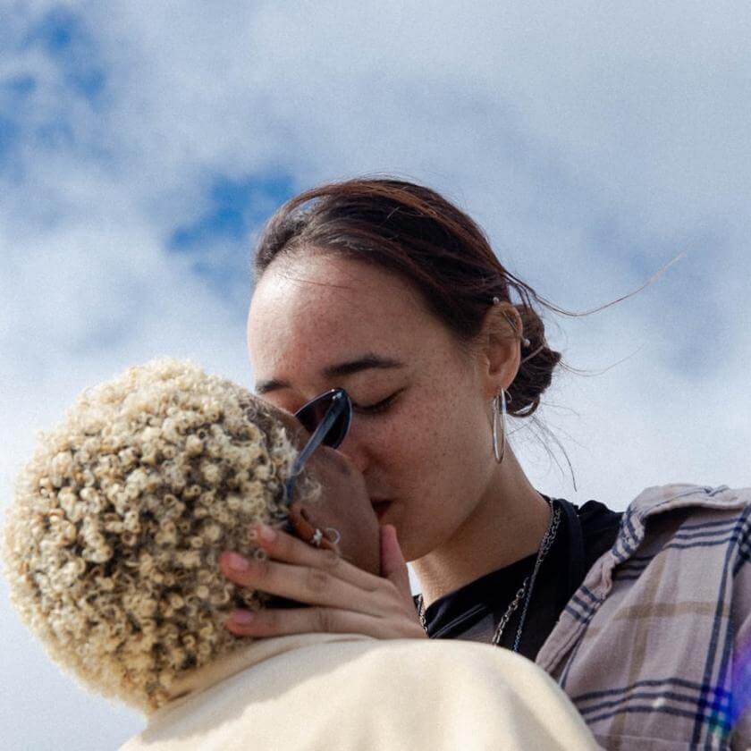 Femme en blanc et femme en chemise à carreaux qui s'embrassent