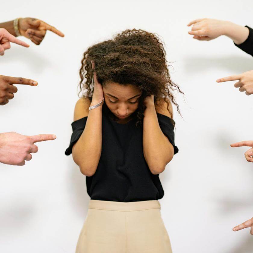 Woman covering her ears and being pointed at by different people