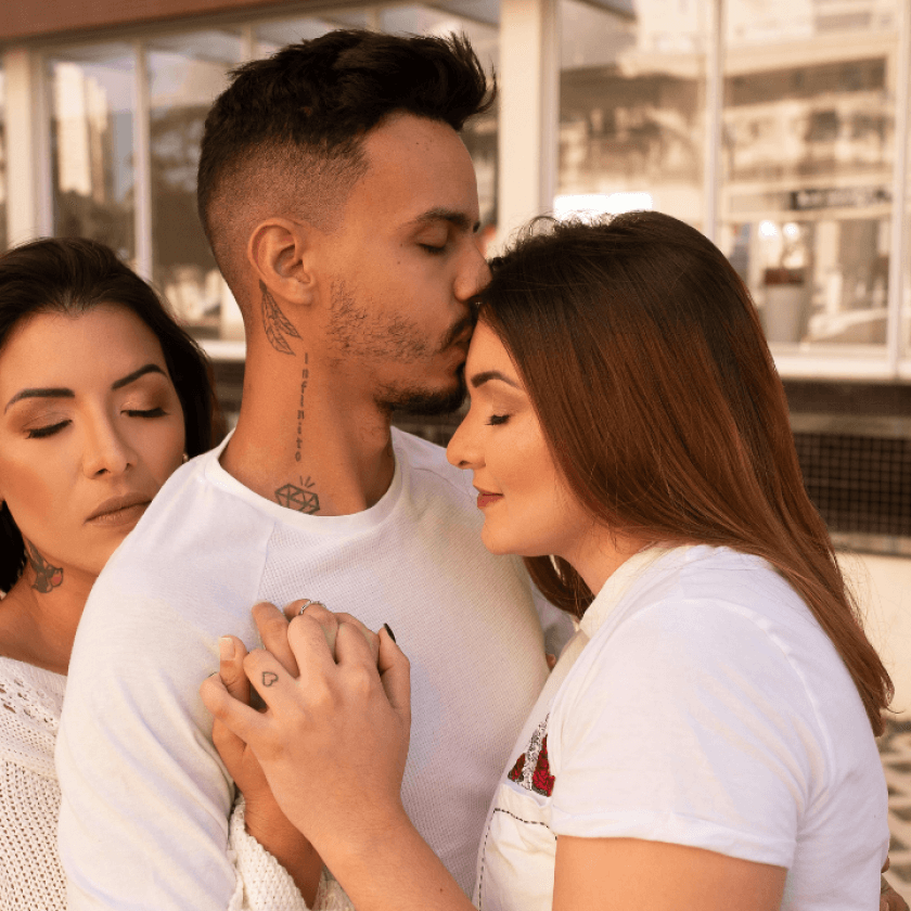 Trouple composé d'un homme et deux femmes qui s'enlacent