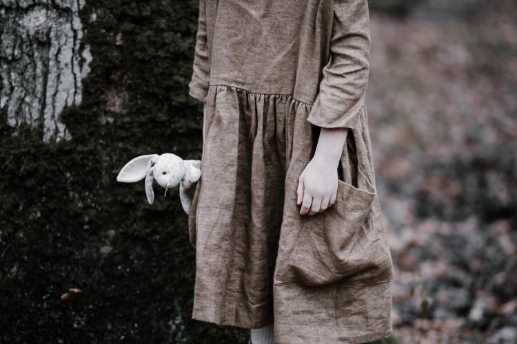 Jeune enfant en robe tenant un lapin en peluche